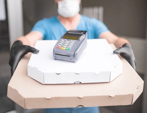A delivery person holding boxes of food with a card reader on top.