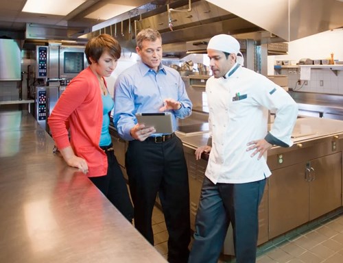 A group of people discussing business around a tablet device.