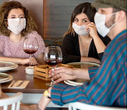 Three people sitting around a table wearing masks.