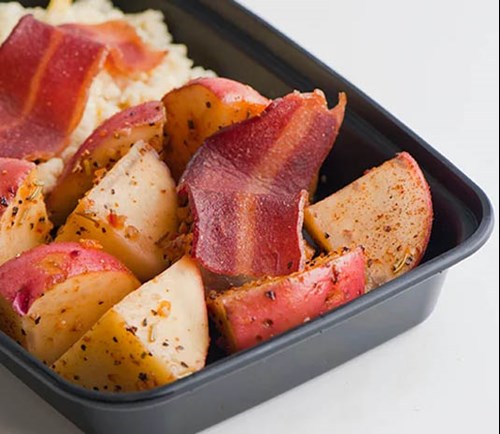 A to-go container filled with potatoes and bacon.
