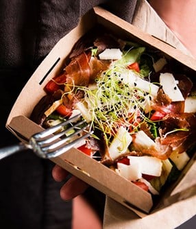 A salad in a takeout container.